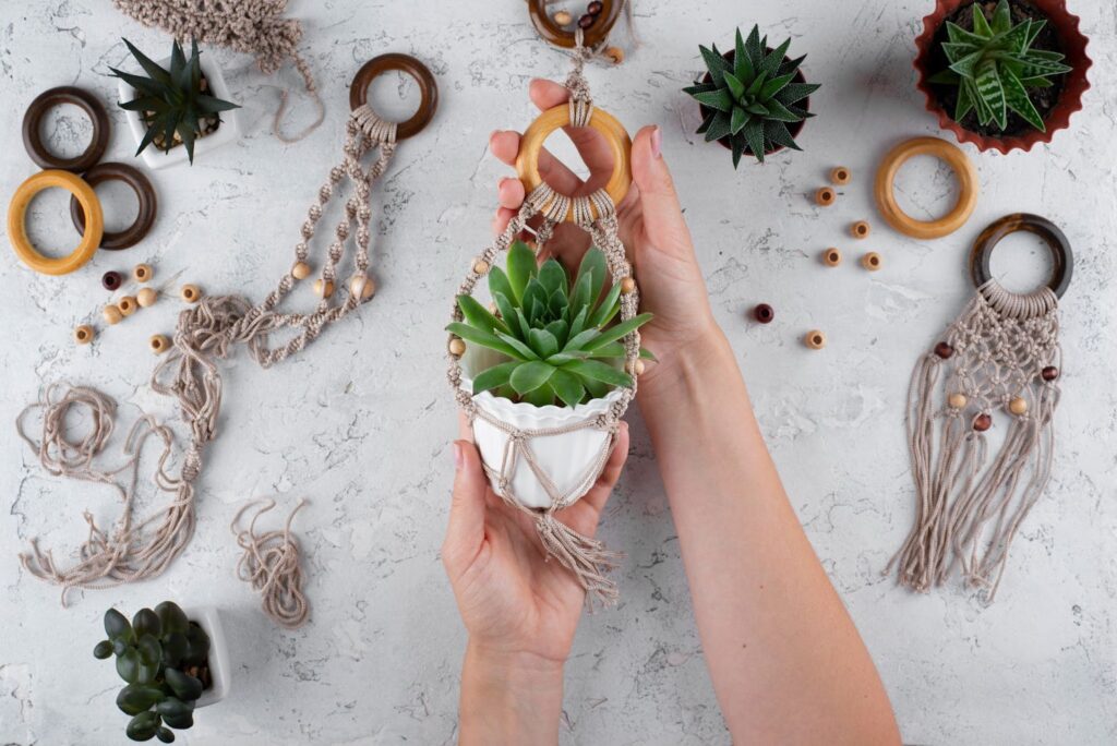 Top view of woman decorating plant with traditional macrame composition